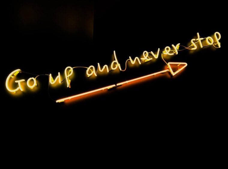 Photograph of a neon sign that reads Go up and never stop