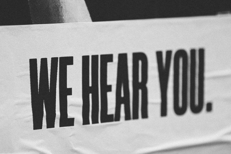Photograph of a poster that reads we hear you