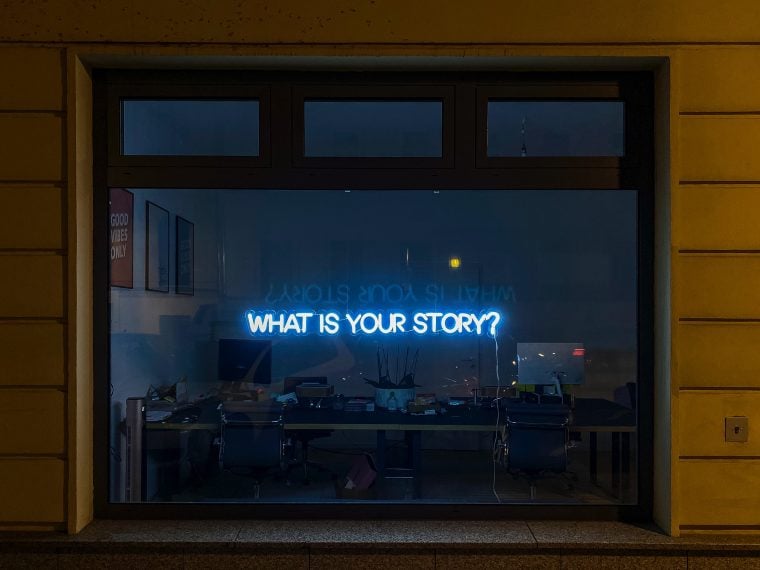 A picture of a neon sign that reads What is your story?